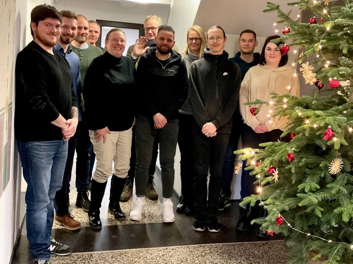 Mitarbeiter-Gruppenfoto neben dem Weihnachtsbaum im Flur aus dem Jahr 2022
